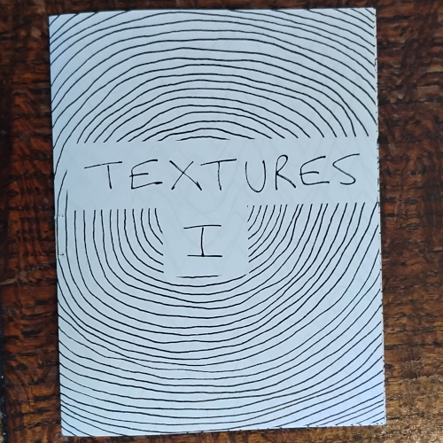 Cover of a minicomic, Textures One. Features the title (with a pretentious Roman numeral for the One) in the center of a spiral that fills the whole cover. 