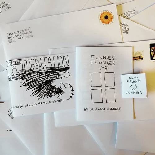 Three minicomics on top of a pile of white 6 by 9 envelopes. 