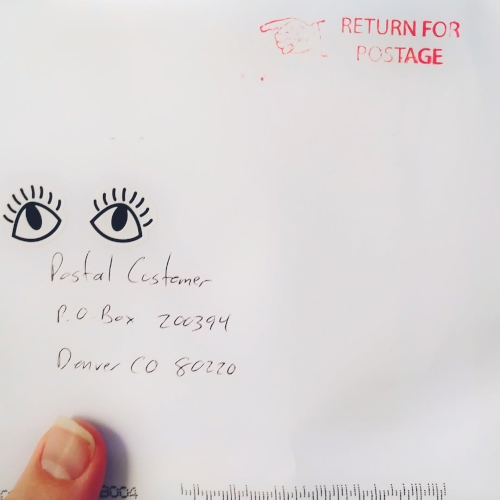 An envelope with my address on it. In the bare upper right corner, the post office stamped it, Return for postage, with a hand pointing back to the return address. Oh and there are a pair of eyes drawn above my address. 
